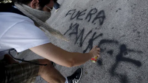 Ein Demonstrant sprayt «Fuera Yankee» auf den Boden