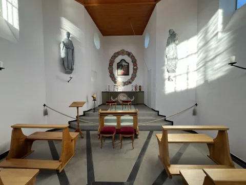 Kapelleninnenraum mit Altar und Gebetsbänken.