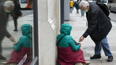 Mann gibt einer bettelnden Person Geld.