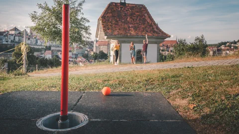 Stadtgolf am Hügel mit drei Personen und Stadtblick auf Fribourg im Hintergrund.