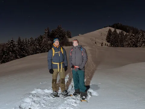 Zwei Männer stehen in der Nacht im Schnee.