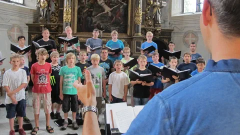 Chorprobe in einer Kirche mit Jungen und Dirigenten.