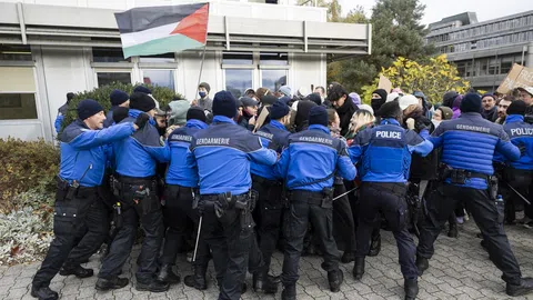 Rund ein Dutzend Polizisten halten die Protestierenden zurück. Darüber weht eine Palästina-Fahne.