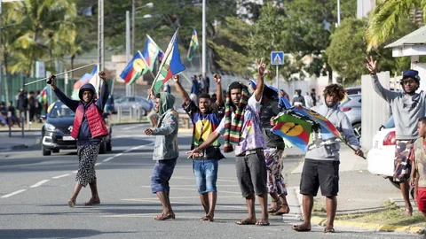 Menschen demonstrieren mit Fahnen auf der Strasse.