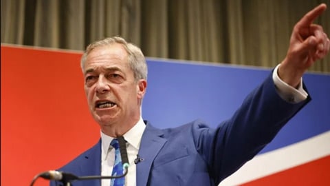 Farage in blauem Anzug zeigt mit dem Finger bei einer Rede.