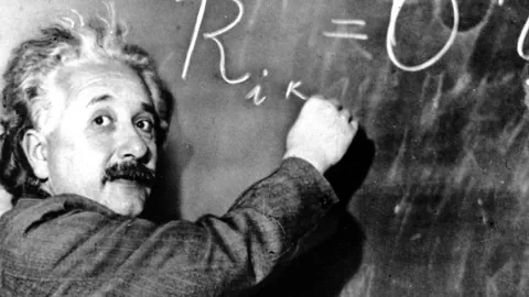 Albert Einstein schreibt eine Formel.