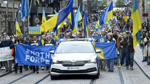 Demonstrationszug mit vielen Ukraine-Fahnen, ein Polizeiauto führt die Menschenmenge an.