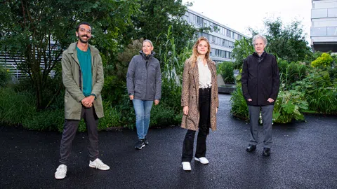 Vier Personen posieren vor einem Gebäude.