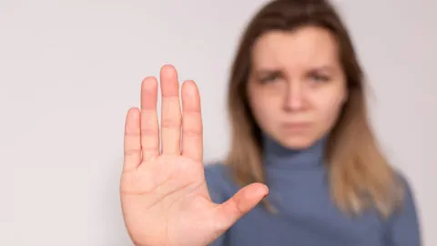 Eine Frau streckt die flache Hand ablehnend von sich weg.