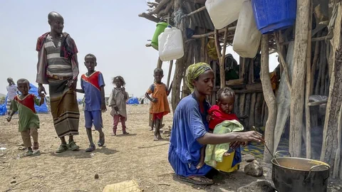 Flüchtlinge vor einer Hütte beim Kochen.