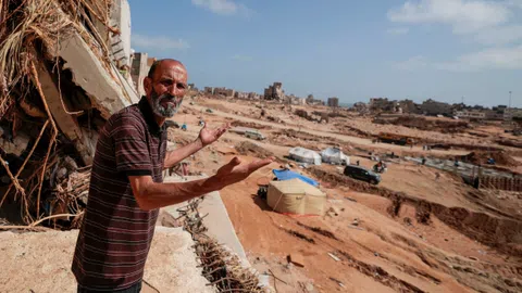 Ein Mann zeigt auf die Zersörung in Derna.