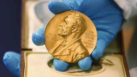 Eine Person hält eine Nobelpreis-Medaille in der Hand.