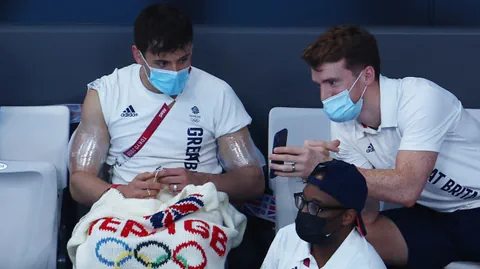 Team GB Athleten mit Masken auf der Tribüne während eines Wettkampfs.