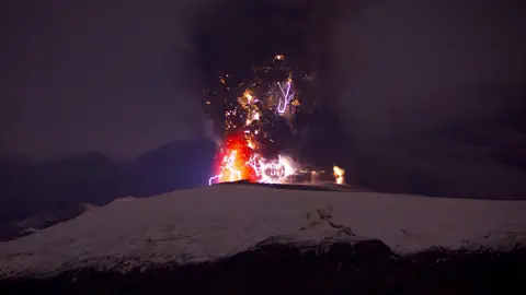 Der schnee- und aschebedeckte Vulkan mit Feuer und Blitzen. 