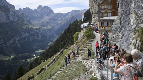 Blick von mit Touristen gefülltem Gehweg auf das Aescher Gasthaus in Schwenden AI 