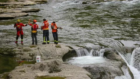 Vier Männer bei Rettungsarbeiten bei einem Wasserfall.