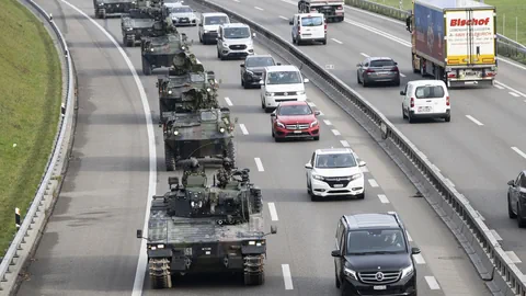 Panzer fahren auf der rechten Spur der Autobahn neben zivilen Fahrzeugen.