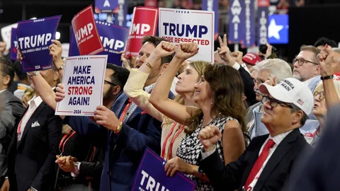 Menschenmenge hält Trump-Schilder auf einer Veranstaltung hoch.