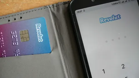 Ein Etui mit Revolut-Kreditkarte auf der linken und einem Smartphone mit der Revolut-App auf der rechten Seite.