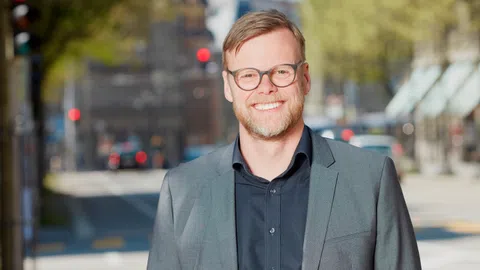 Ein blonder junger Mann mit Brille und Dreitagebart