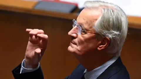 Barnier mit Brille und Anzug spricht im Parlament.