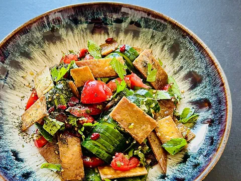 Frittierte Fladenbrotstücke, knackige Salatgurken, reife Tomaten, frischer Petersilie, Minze und Gewürze