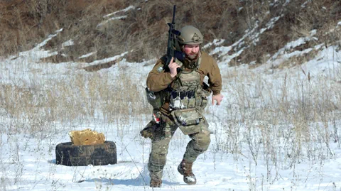 Soldat in Tarnkleidung rennt im Schnee.