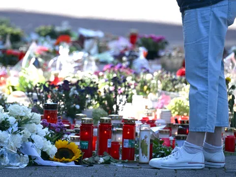 Blumen, Kerzen und Gedenkgegenstände auf dem Boden.