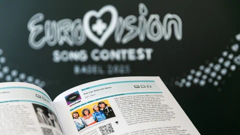 Man sieht eine Seite aus dem Unterrichtsmaterial. Im Hintergrund steht auf einer Wandtafel Eurovision Song  Contest