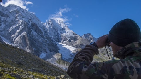 Mann mit Feldstecher schaut in Richtung Cengalo.