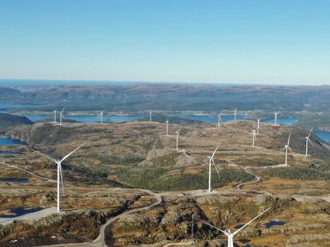 Windturbinen stehen in der Natur. Gewässer sind zu sehen.