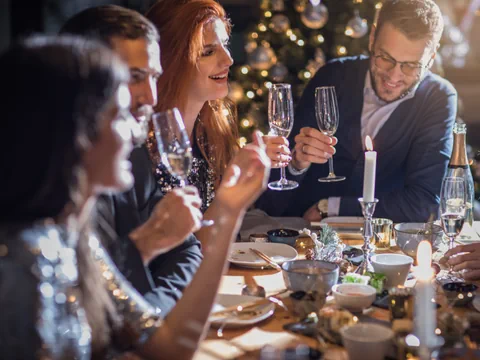 Gruppe von Menschen bei einem festlichen Abendessen mit Kerzen und Sektgläsern.