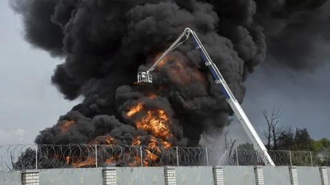 Feuerwehrmann bekämpft Grossbrand mit Kran.