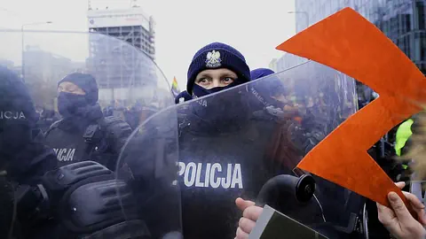 Eine Abtreibungsrecht-Demonstrantin hält das Protest-Emblem einer Polizistin in Kampfmontur entgegen.