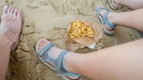 Auf dem Bild ist eine Portion Pommes im Sand zu sehen.