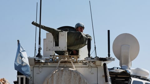 Soldat in gepanzertem Fahrzeug mit UN-Flagge.