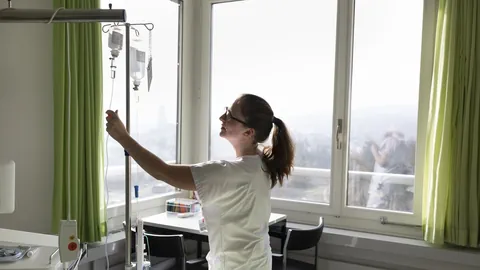 Unispital Bern, Insel: Eine Krankenschwester überprüft die Infusionsflaschen eines Patienten.