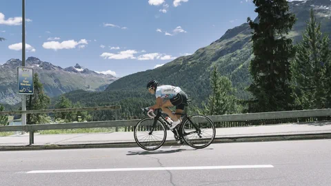 Radfahrer auf der Strasse in bergiger Landschaft.