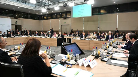 Menschen in einem Konferenzraum an einem runden Tisch bei einer Besprechung.