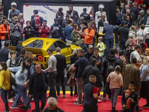 Menschenmenge um gelbes Auto auf einer Messe.