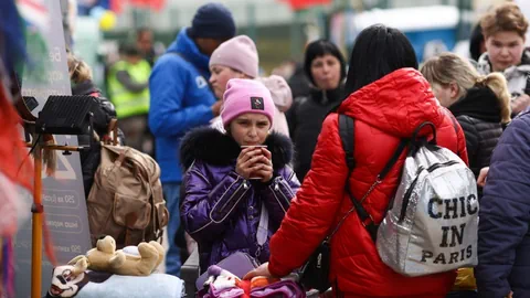 Geflohene Frauen und Kinder, sie trinken etwas zur Stärkung.