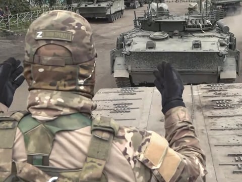 Russischer Soldat dirigiert Panzer auf einer Strasse.