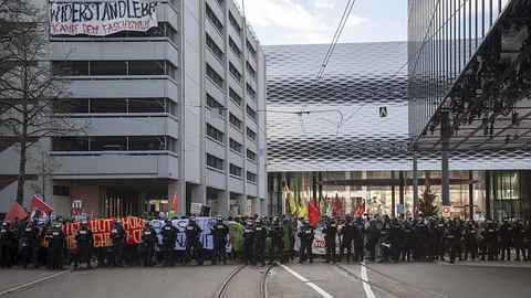 Anhänger der Pnos demonstrieren auf der Strasse und werden von Sicherheitskräften blockiert.