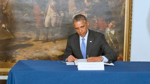 Obama schreibt in ein Buch.