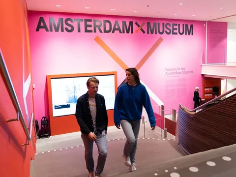 Zwei Personen gehen eine Treppe im Amsterdam Museum hinunter.