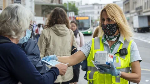 Eine Mitarbeiterin der Basler Verkehrs-Betriebe  verteilt Masken.