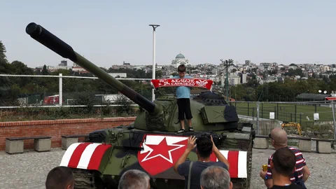 Ein kleiner Bub steht auf einem rot-weiss bemalten Panzer vor dem Fussballstadion in Belgrad