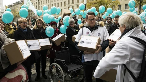 Verschiedene Pflegefachpersonen in weissen Kitteln reichen die Unterschriften zur Pflege-Initiative vor dem Bundeshaus ein.