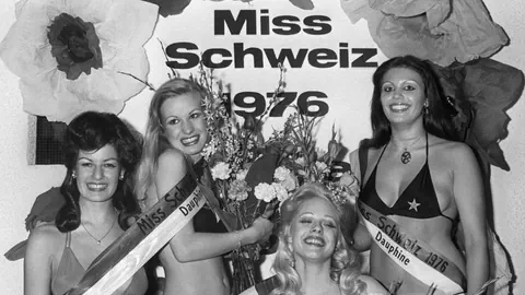 Spärlich bekleidete junge Damein mit Scherpe an Miss Schweiz Wahlen posieren lächelnd für ein Siegerfoto.