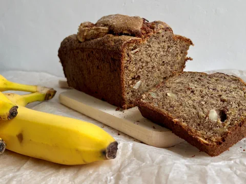 Banana Bread aufgeschnitten mit zwei Bananen als Deko. 